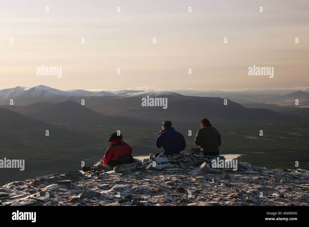 Three Walkers Enjoying the View Over Loch Morlich From the Summit of Meall a Bhuachaille Cairngorms Scotland in Winter Stock Photo