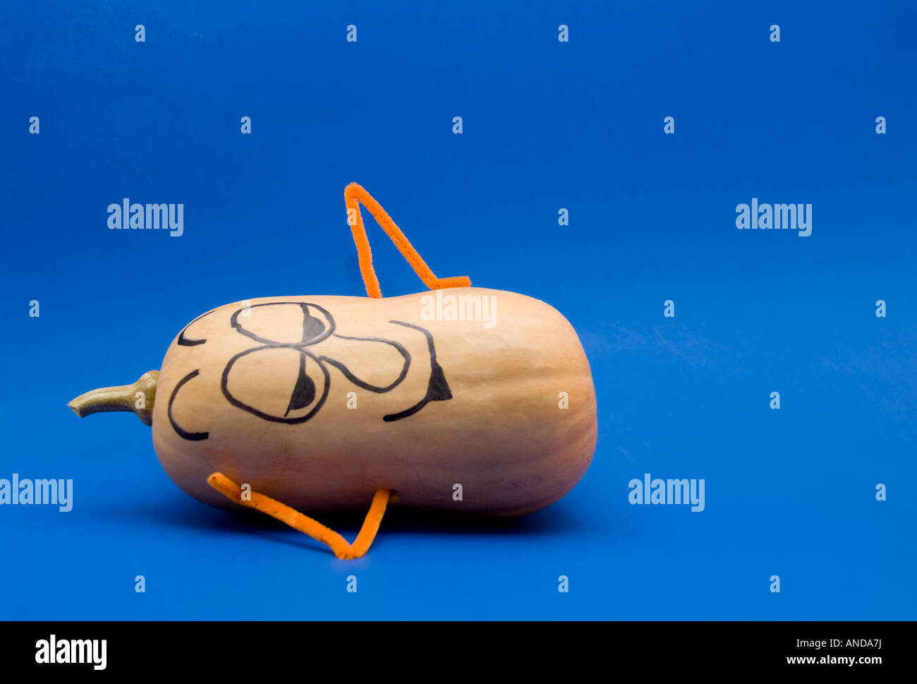 A butternut squash against a blue background used as a funny character with painted on face. Cutout. Stock Photo