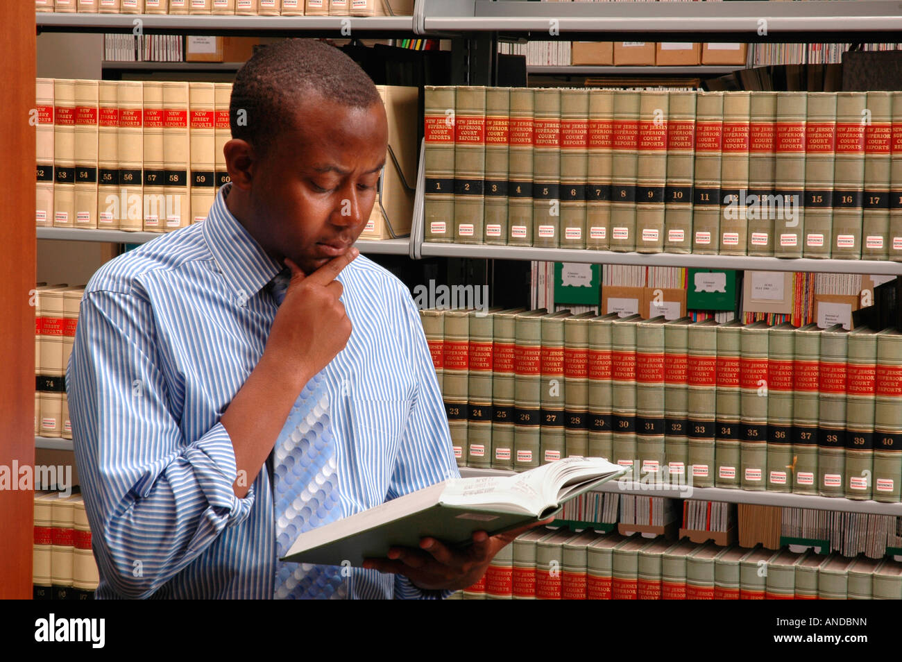 A black college student or young lawyer reading a law book in a library