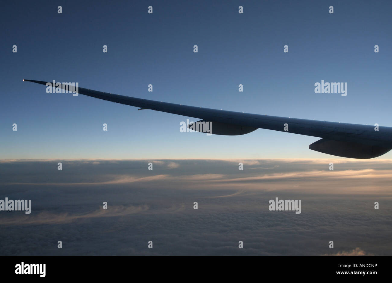 Air travel and aviation. Boeing 777 aircraft wing at dawn while flying at high altitude. Stock Photo