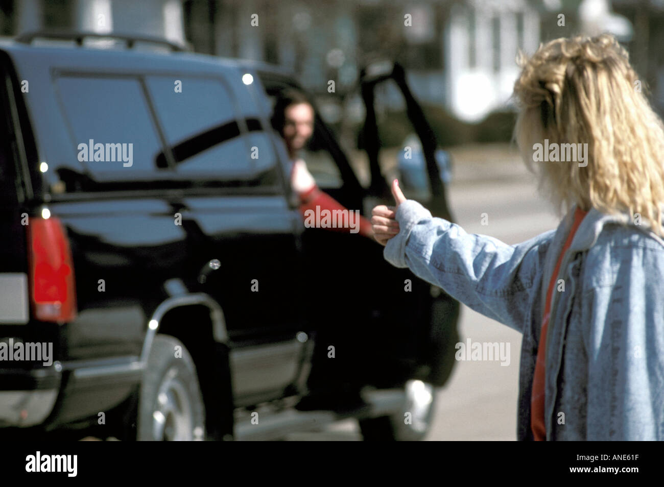 Teen Female Hitch Hiker attempts to get a ride in a car as she runs away from home Stock Photo