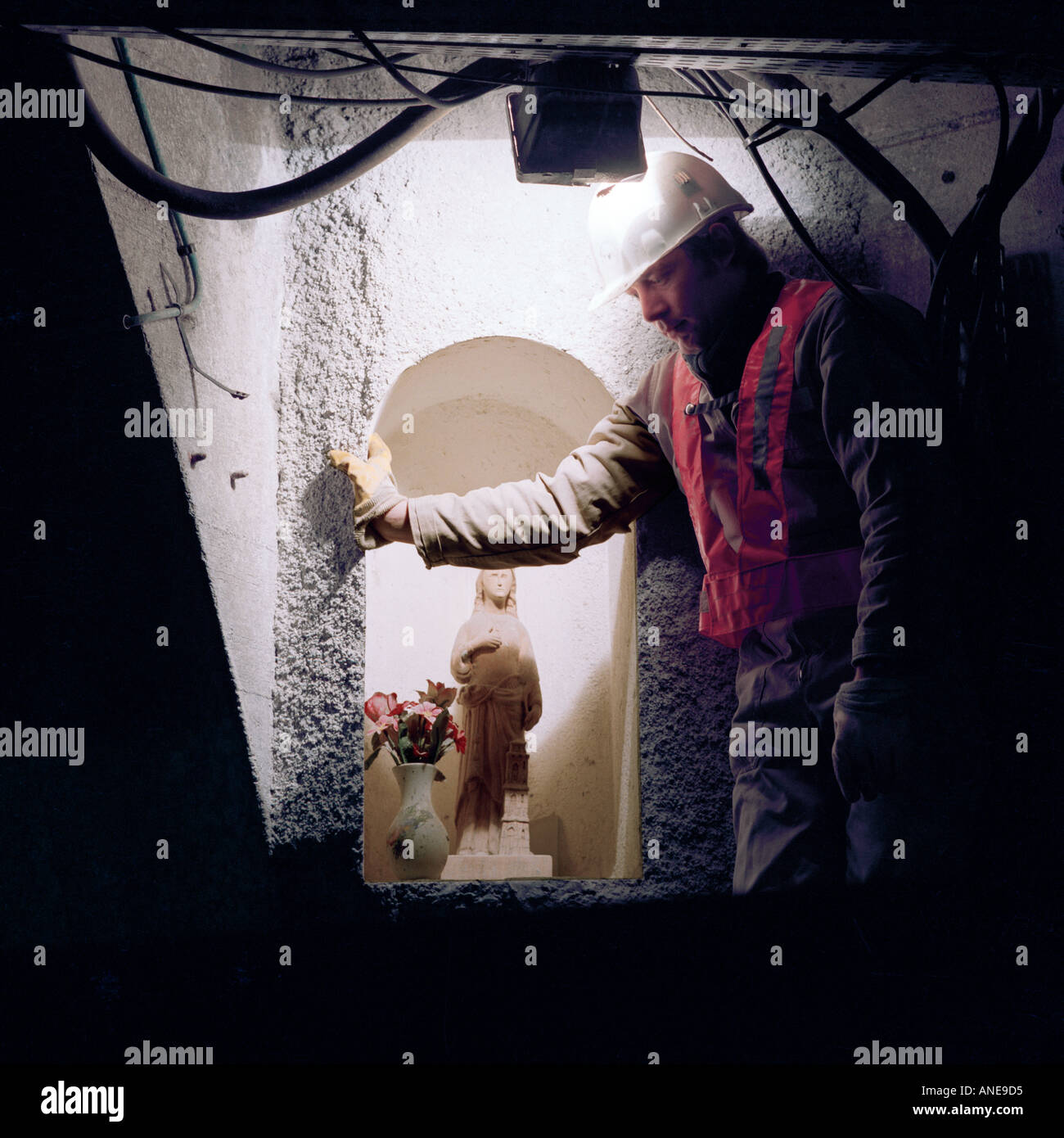 French Channel Tunnel worker pauses by a statue of St Barbara the