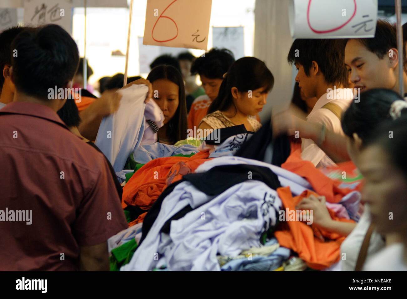 A Crowd of Chinese Shoppers Aggressively Digging Through Clothes in a Sale  Bin, Guangzhou, China Stock Photo
