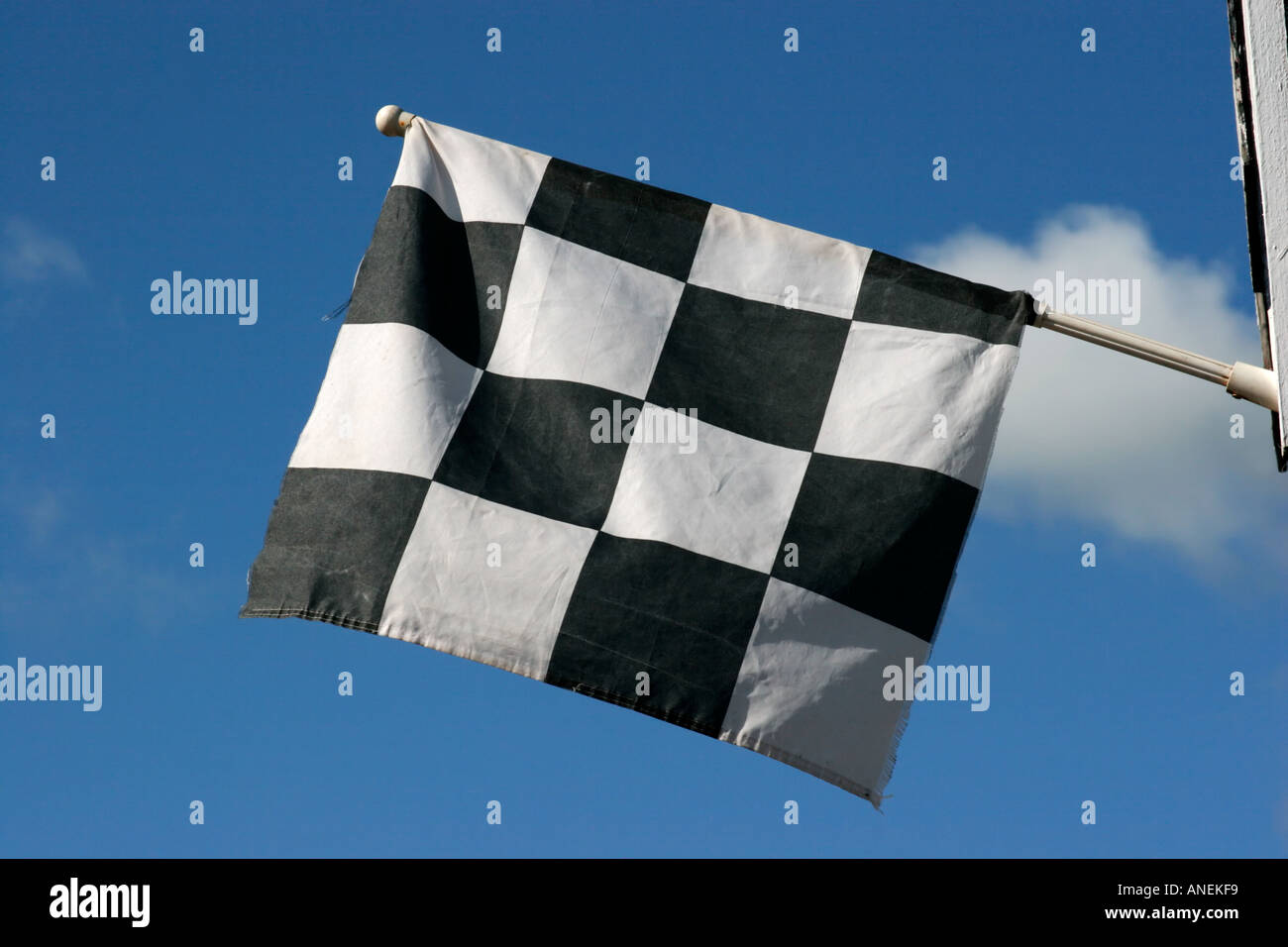 Chequered black and white flag against blue sky Stock Photo