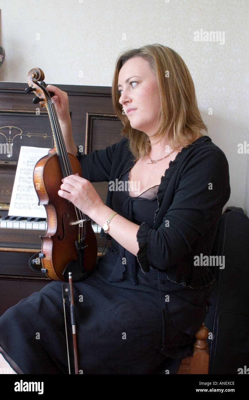 Irish woman in a black dress tuning a violin. Stock Photo