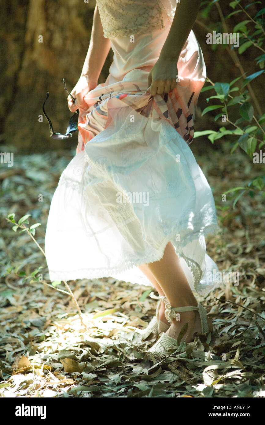 Young woman standing in woods, lifting up skirt, waist down Stock Photo