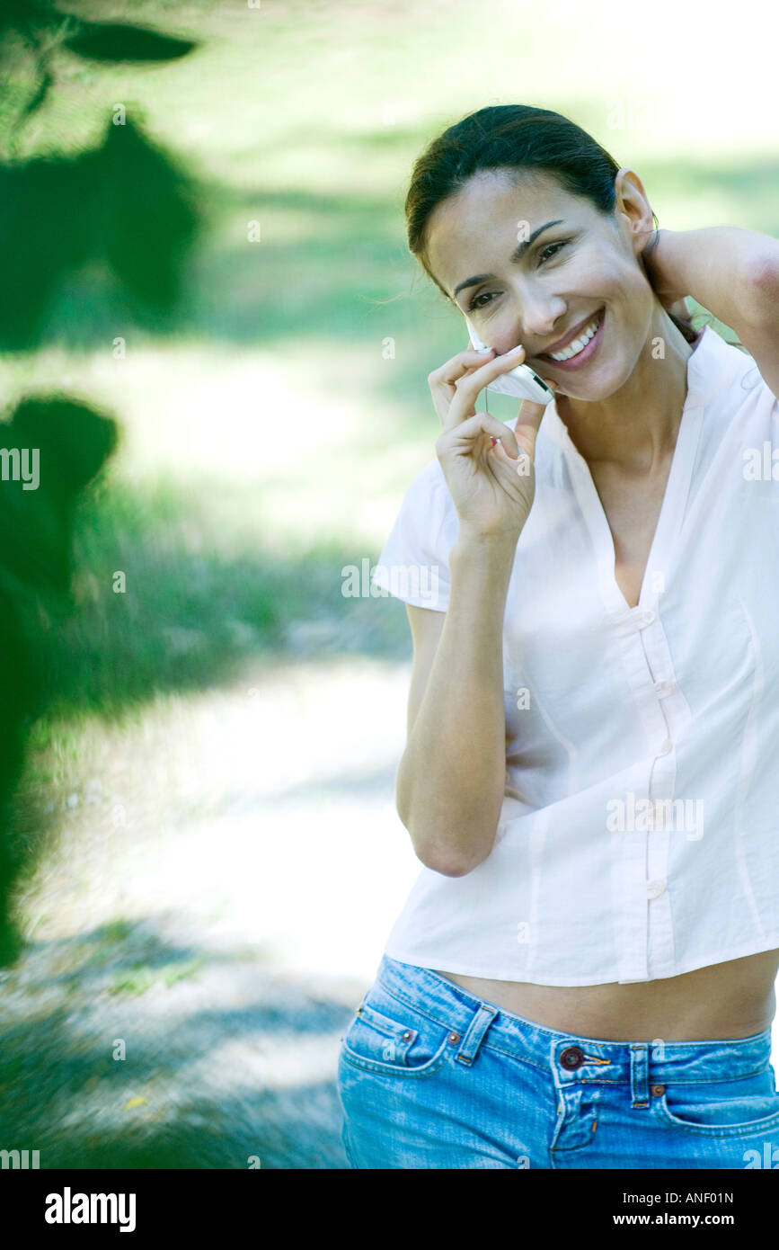 Woman using cell phone outdoors, smiling Stock Photo