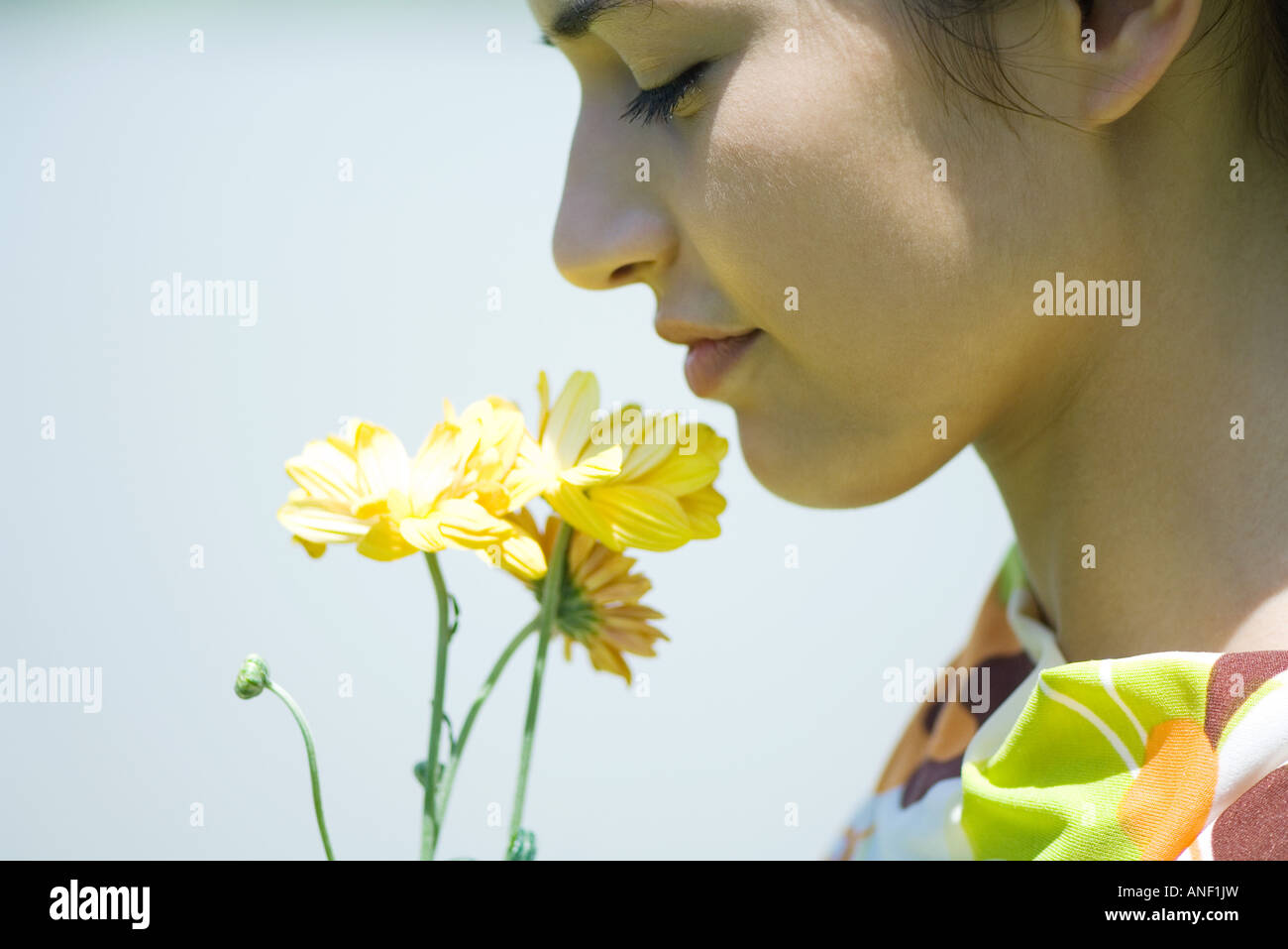 Young woman smelling flowers, profile, close-up Stock Photo