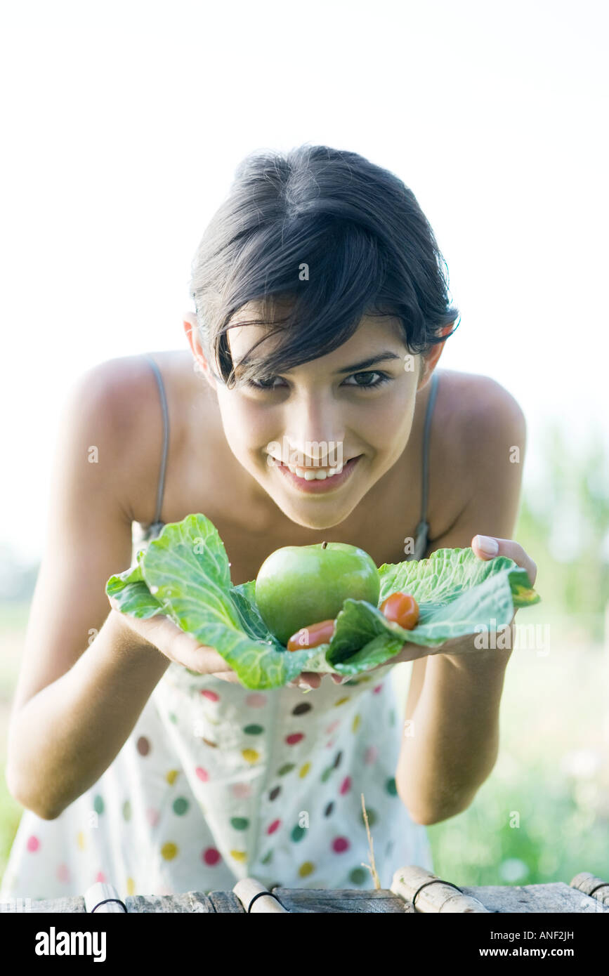 Young woman holding up fresh produce, smiling at camera Stock Photo