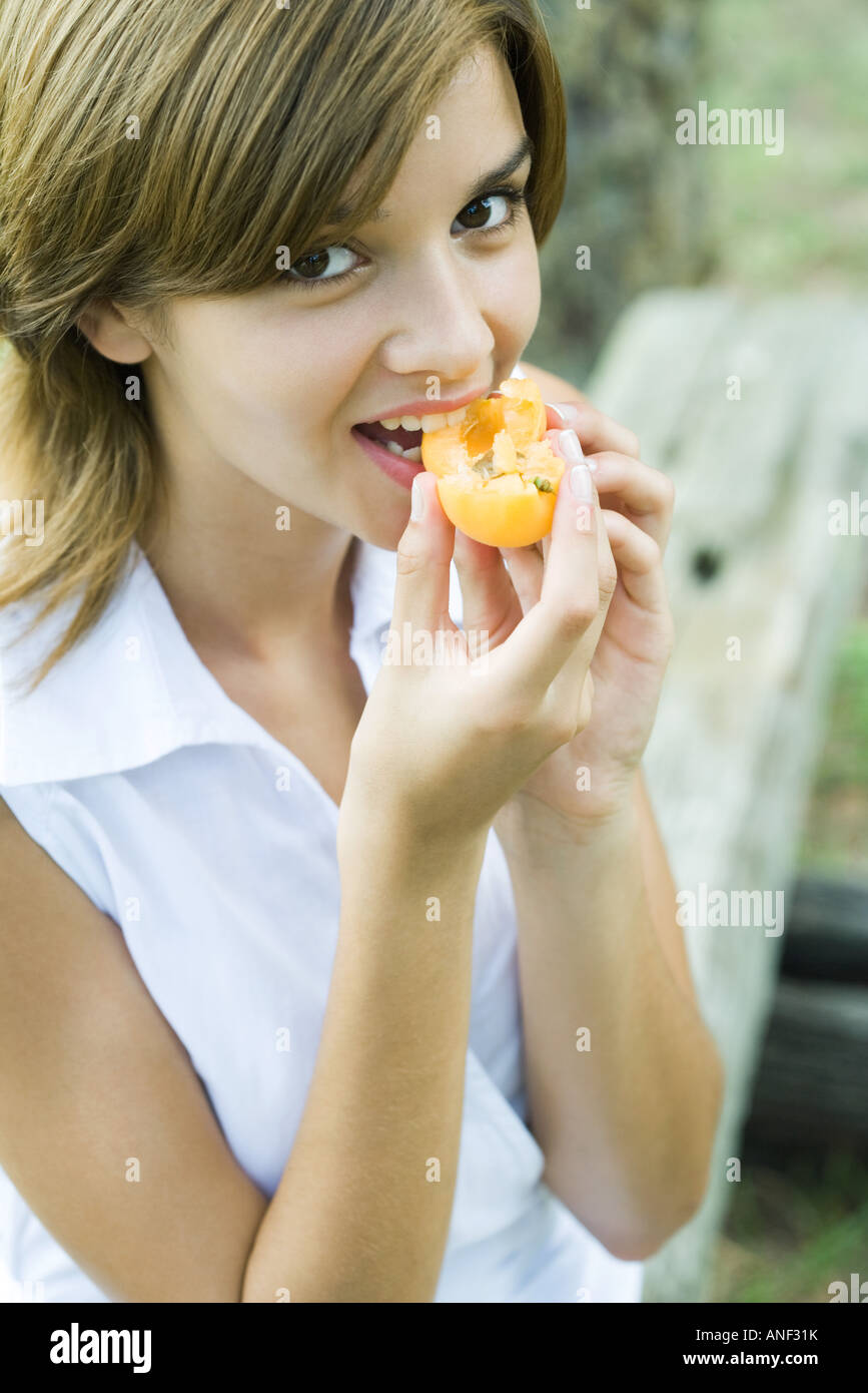 Young woman biting into apricot, looking at camera Stock Photo