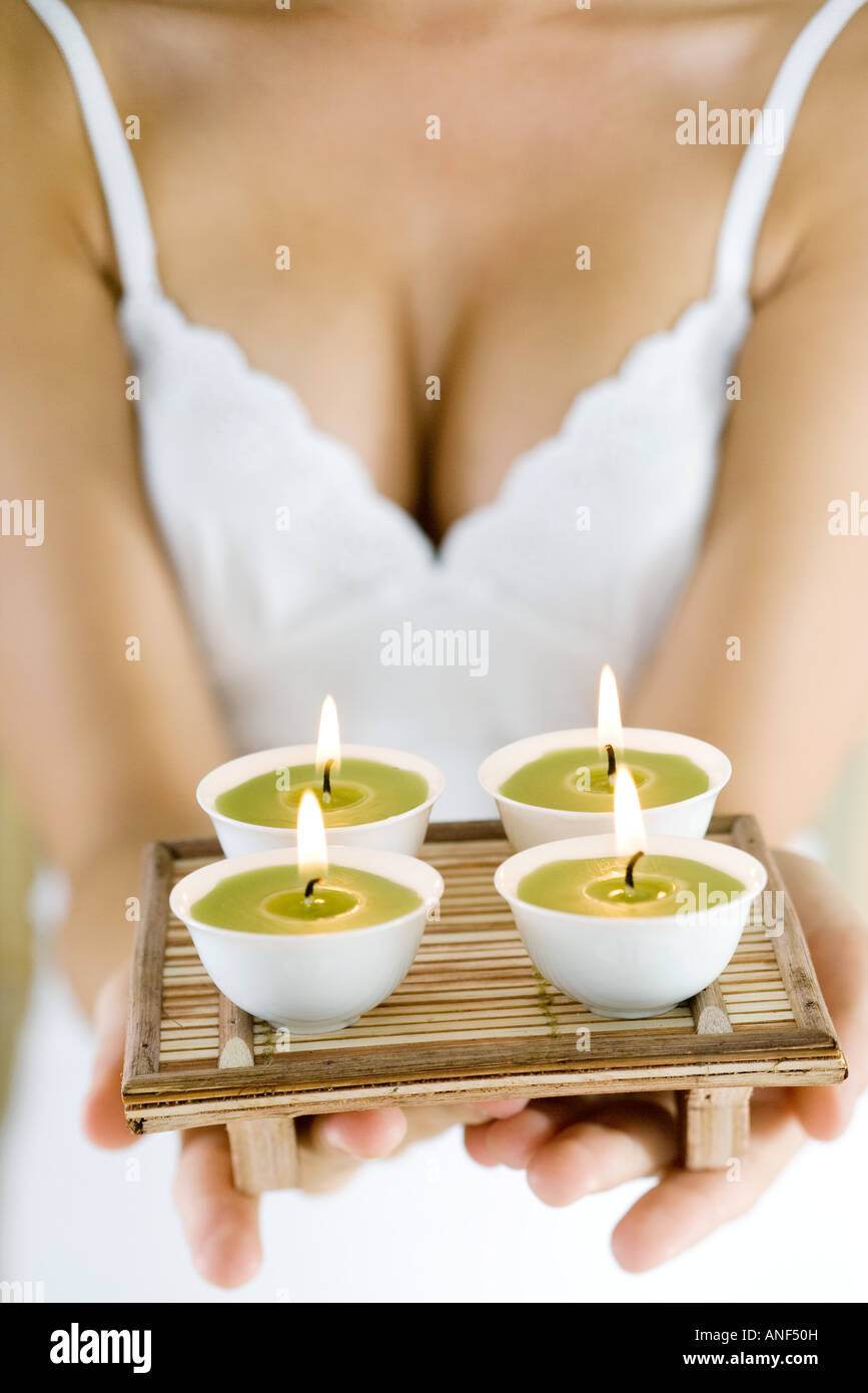 Woman holding out tray of candles, cropped Stock Photo
