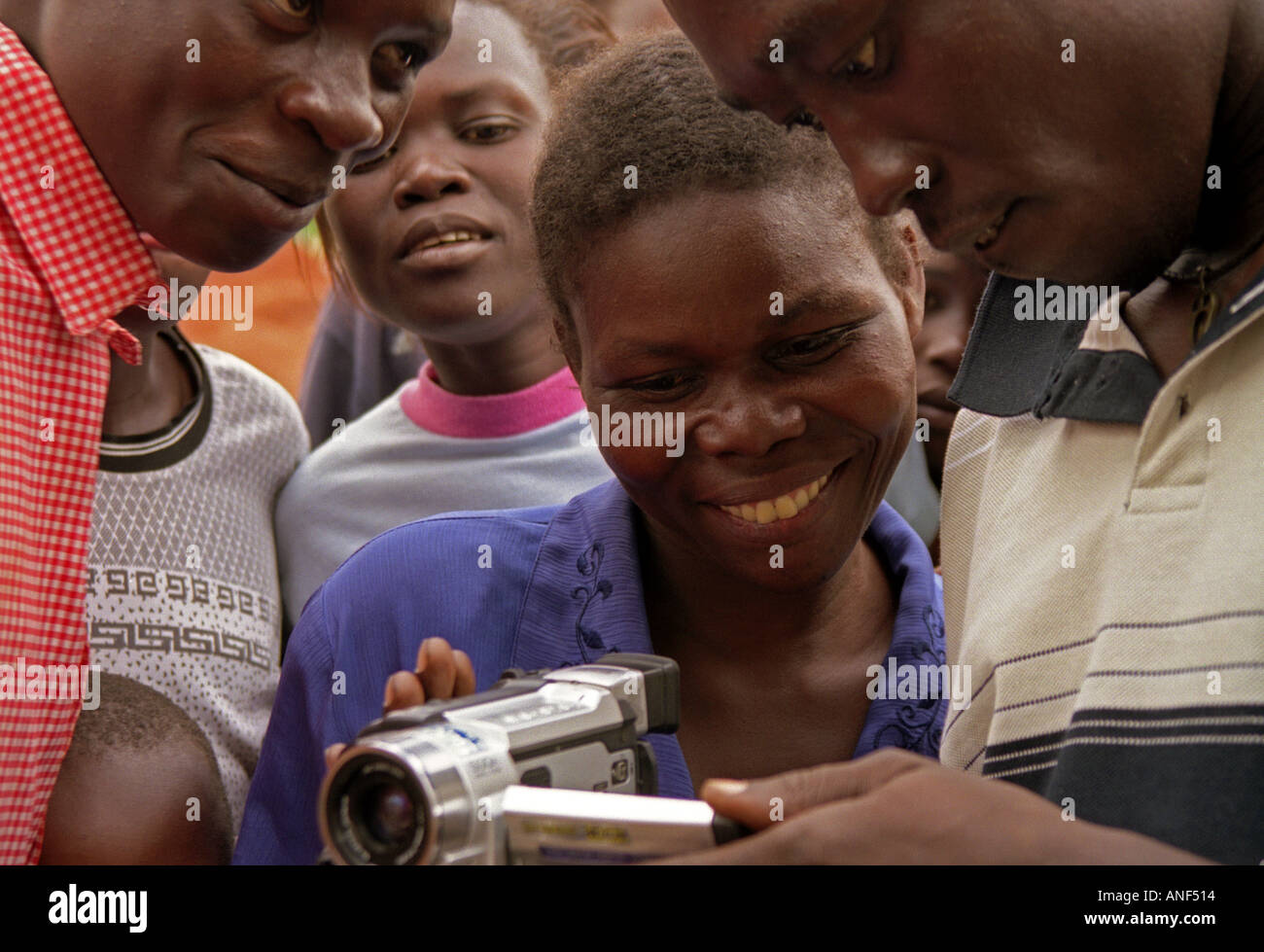 Group of people of Acholy shanty town gathered & watching amused images of themselves on video Kampala Uganda East Africa Stock Photo
