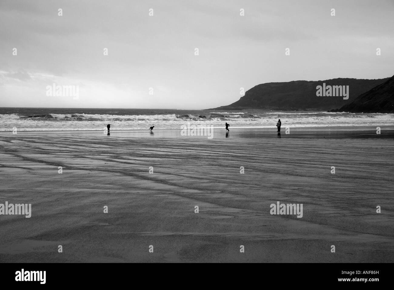 'Black and white' photograph four distant figures on 'Caswell Bay' 'Gower Peninsula', 'Wales' Stock Photo