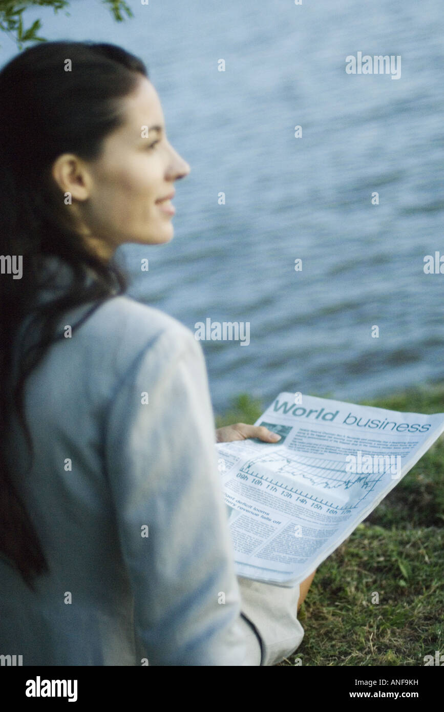 Businesswoman reading newspaper, lake in background Stock Photo