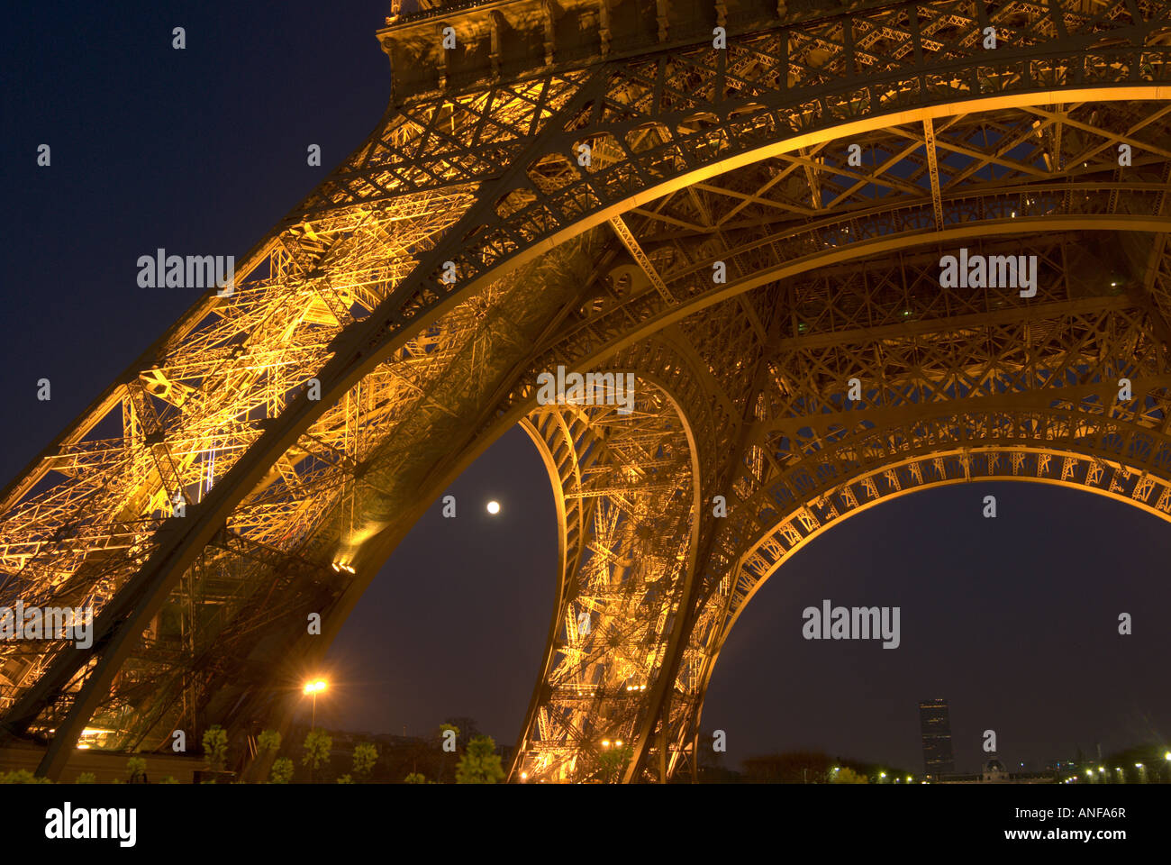 Section of lower level of eiffel tower by night with full moon Stock Photo