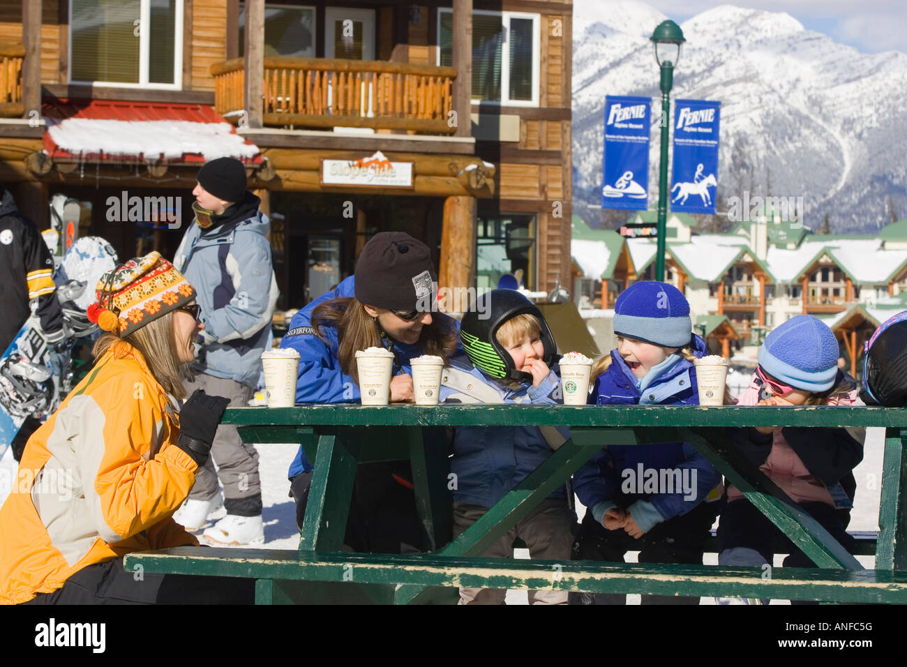 Two mothers enjoy hot chocolates with daughters at Fernie Alpine Resort, Fernie, British Columbia, Canada. Stock Photo