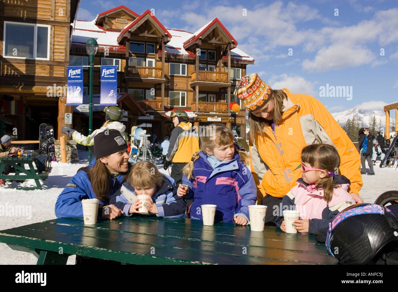 Two mothers enjoy hot chocolates with daughters at Fernie Alpine Resort, Fernie, British Columbia, Canada. Stock Photo