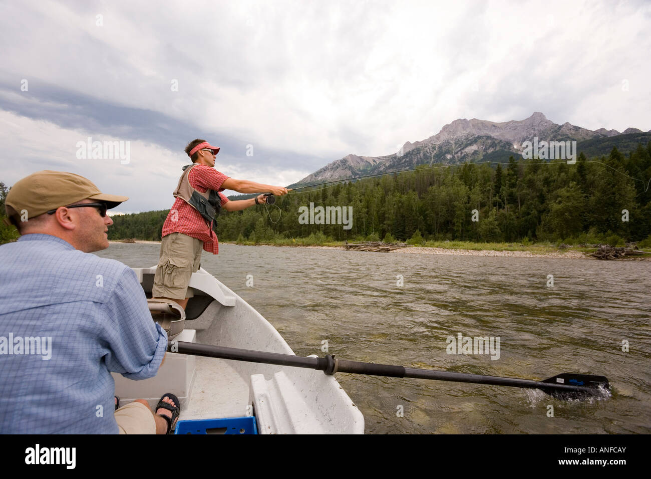 Young men fly fishing on the Elk River from a dory while guide watches, Fernie, East Kootenays, British Columbia, Canada. Stock Photo