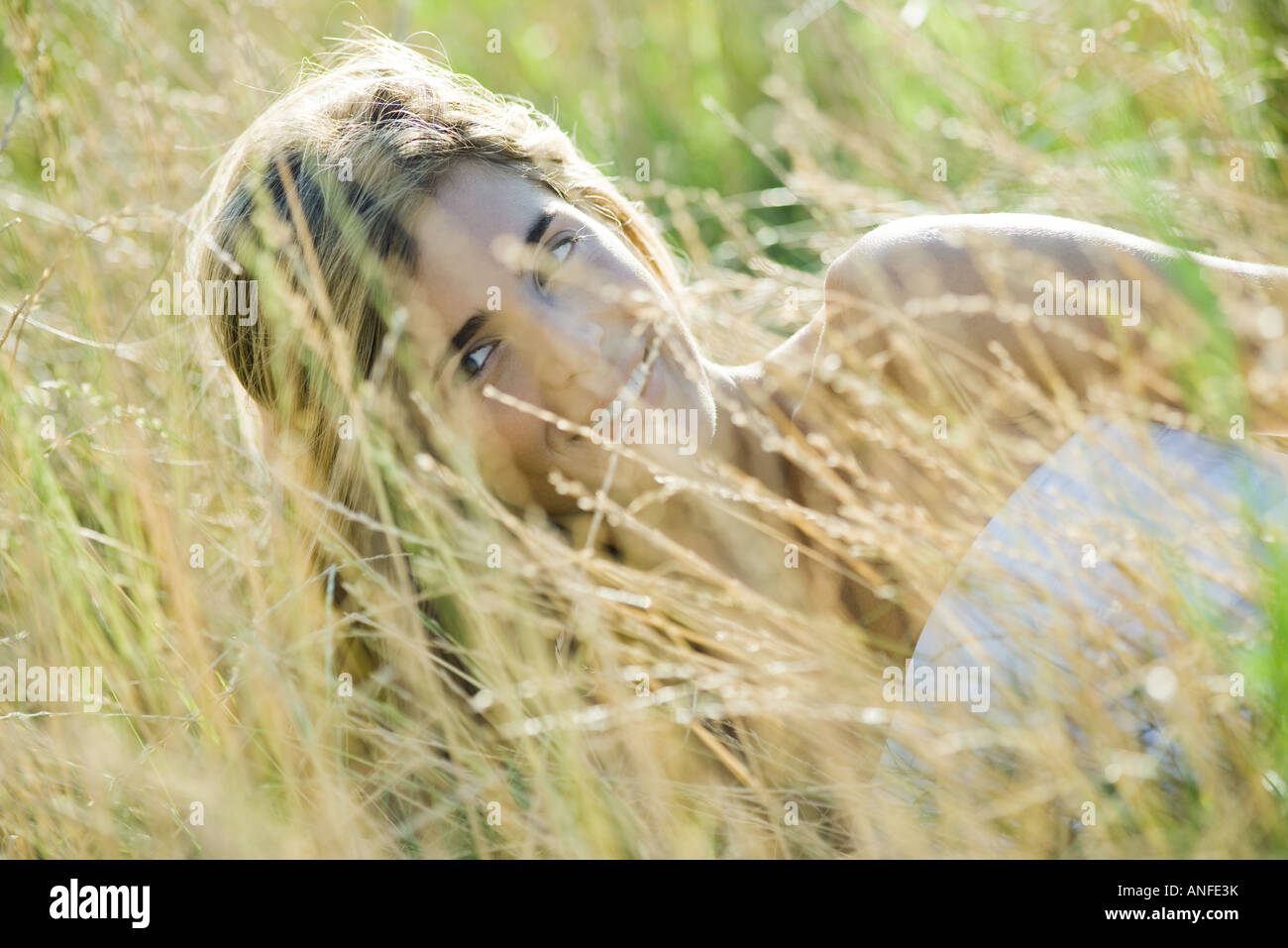 Young woman reclining in tall grass, smiling Stock Photo - Alamy