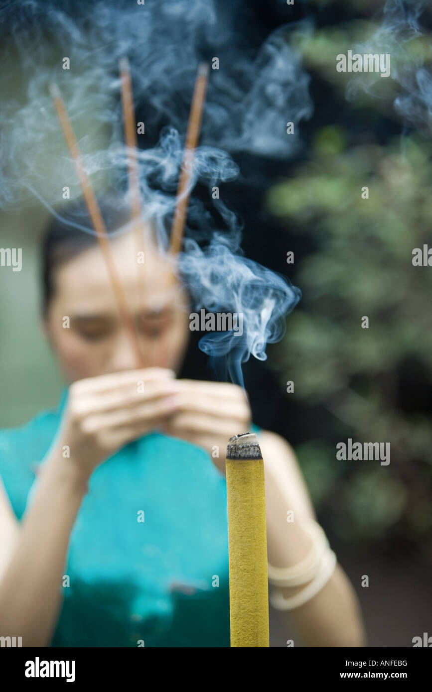Young woman wearing traditional Chinese clothing, holding up incense Stock Photo Alamy