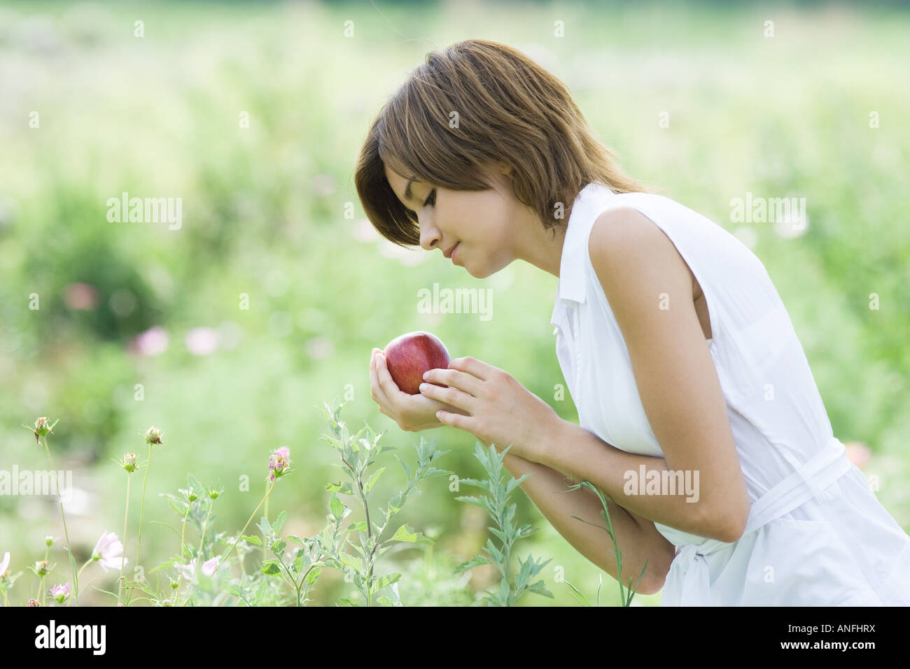 Young woman standing in garden, holding apple Stock Photo
