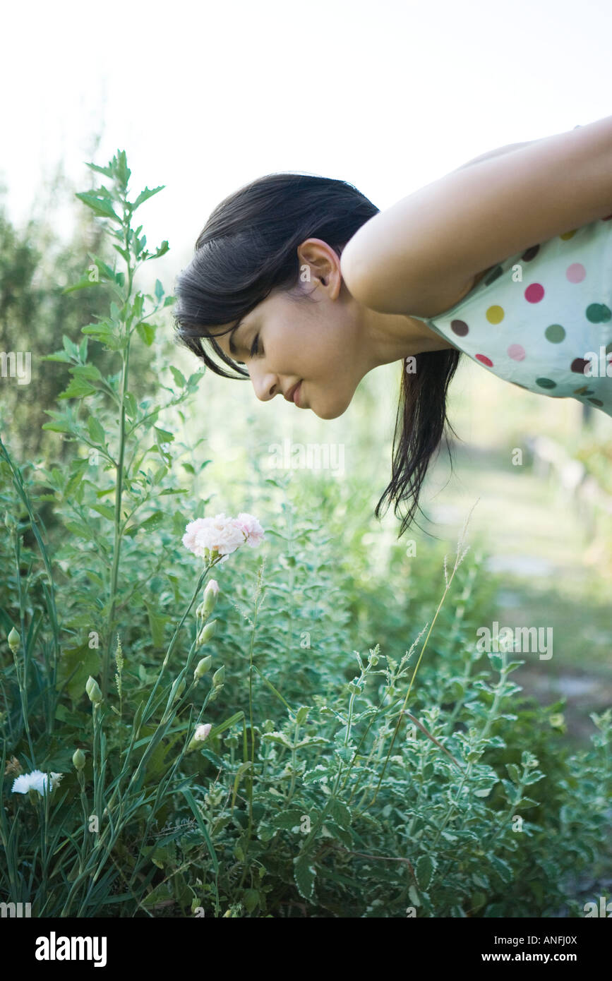 Young woman bending over to smell flowers in garden Stock Photo Alamy