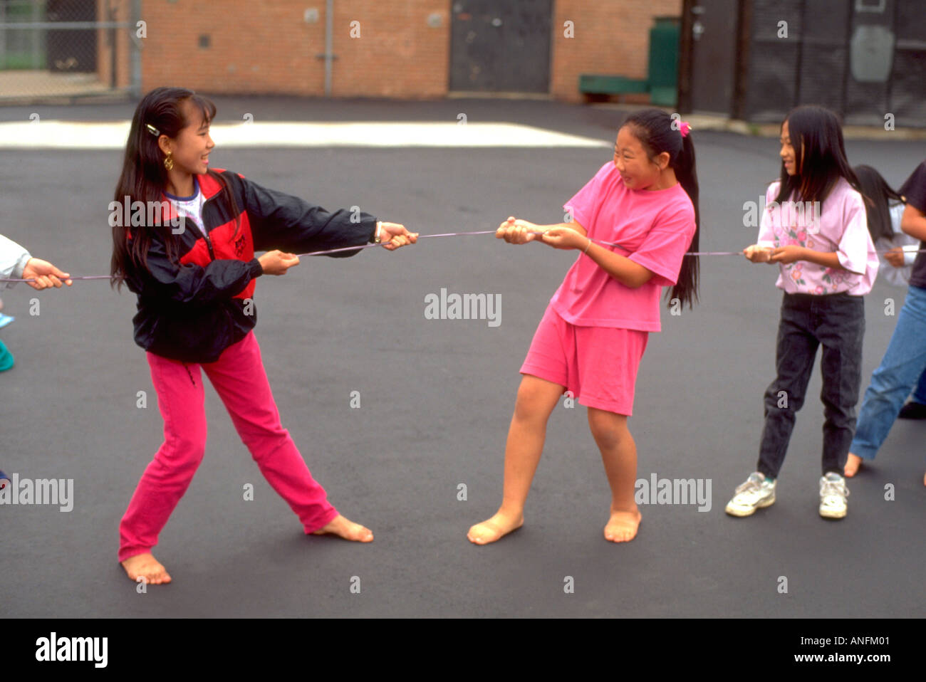 Asian American students age 11 playing tug of war at recess during summer school. Holland School Minneapolis Minnesota USA Stock Photo