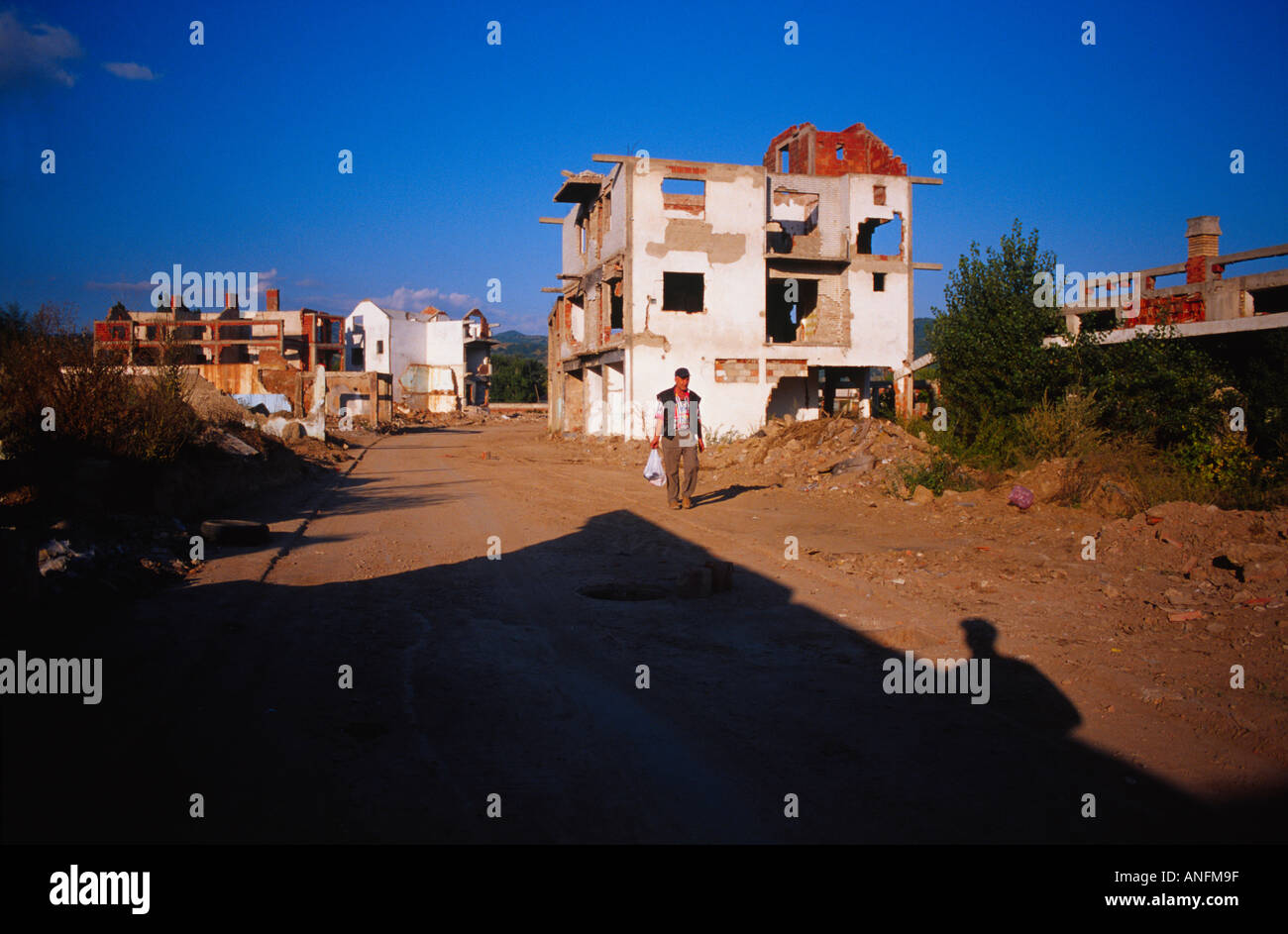 a man walks by abanedoned serb houses, mitrovica, kosovo Stock Photo
