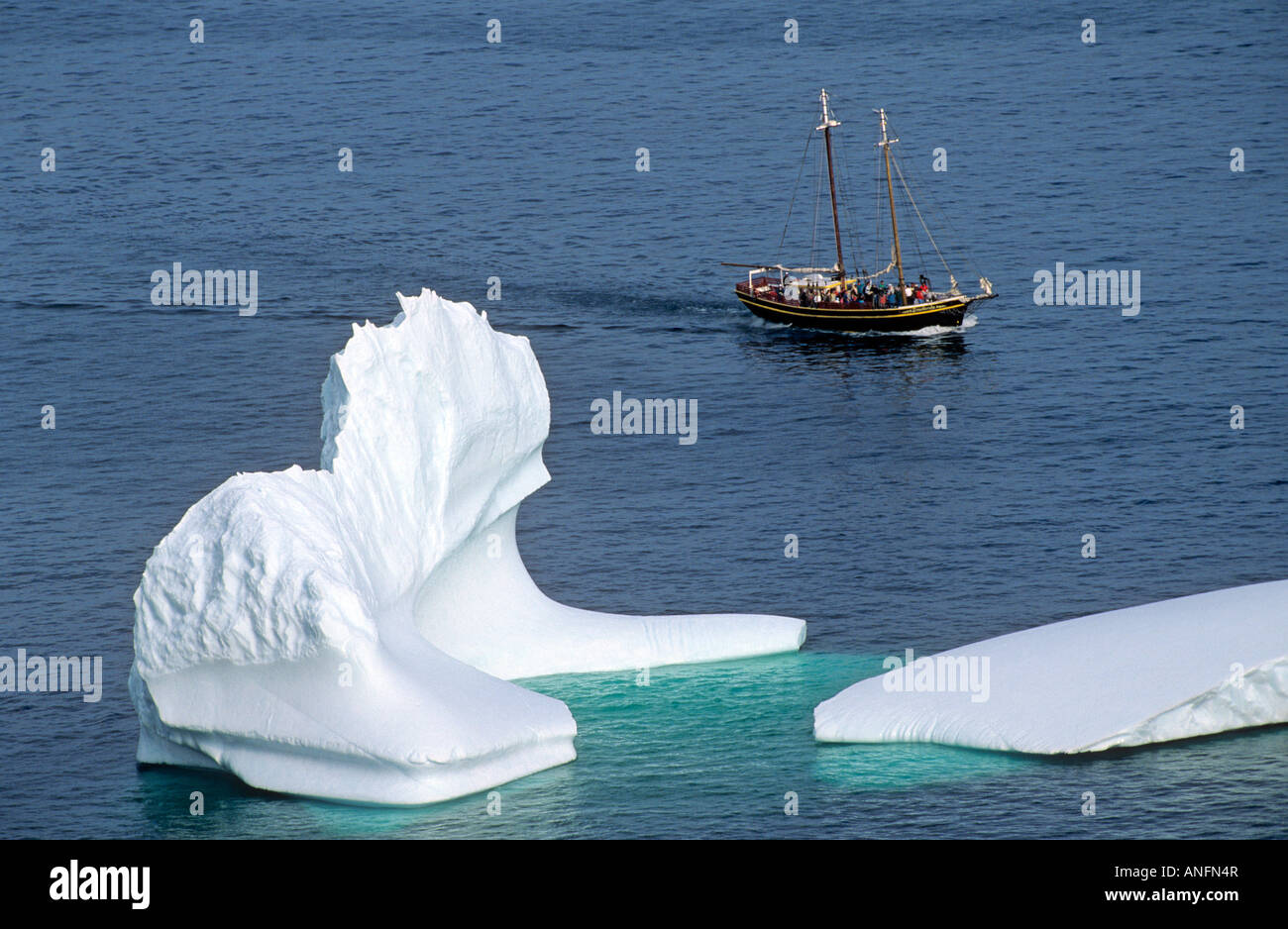 Iceberg and sailing ship off St. John's Newfoundland, Canada. Stock Photo