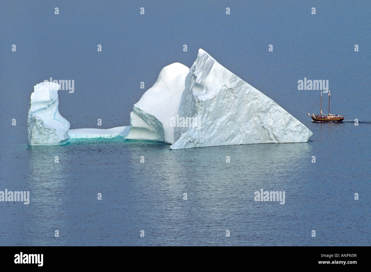 Iceberg and sailing ship off St. John's Newfoundland, Canada. Stock Photo