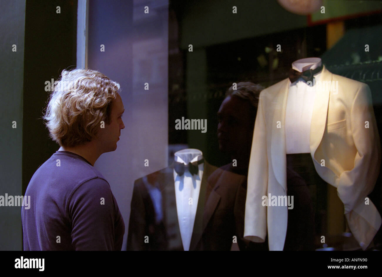 Scruffy man looking at dinner jackets in shop window Stock Photo