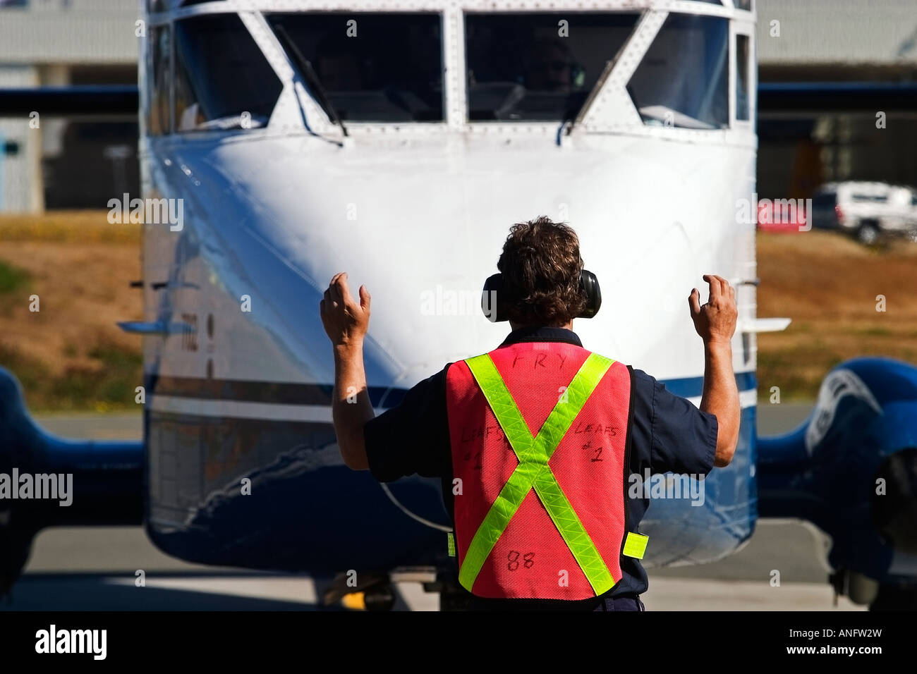 Ramp attendant directing regional airline on tarmac, Comox, British Columbia, Canada Stock Photo