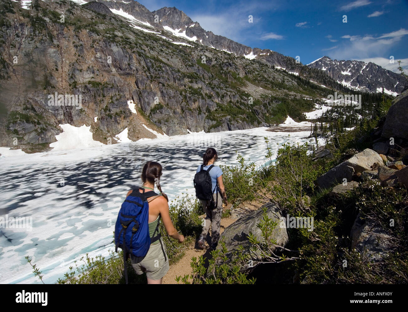 Two women hikers hiking beside frozen Kokanee Lake, Kokanee Glacier