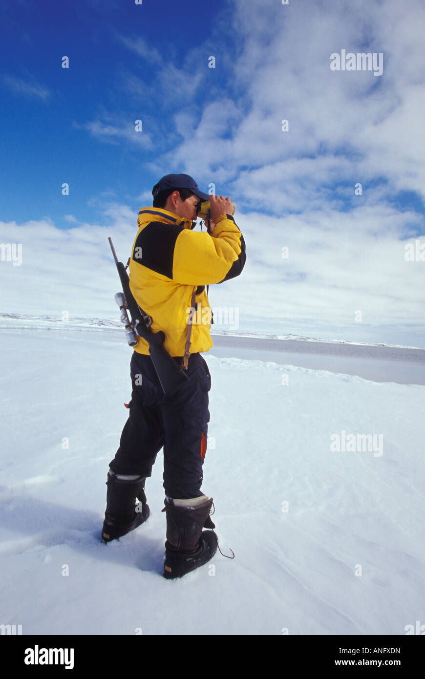 Young Inuit hunter scans horizon at ice flow edge near village of