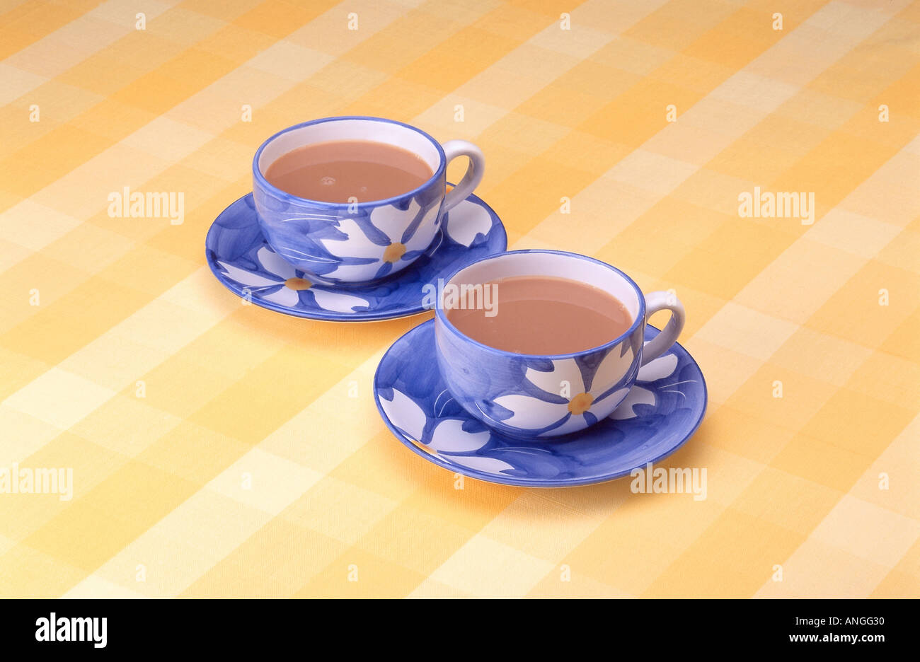 Two blue tea cups on yellow checked table cloth Stock Photo