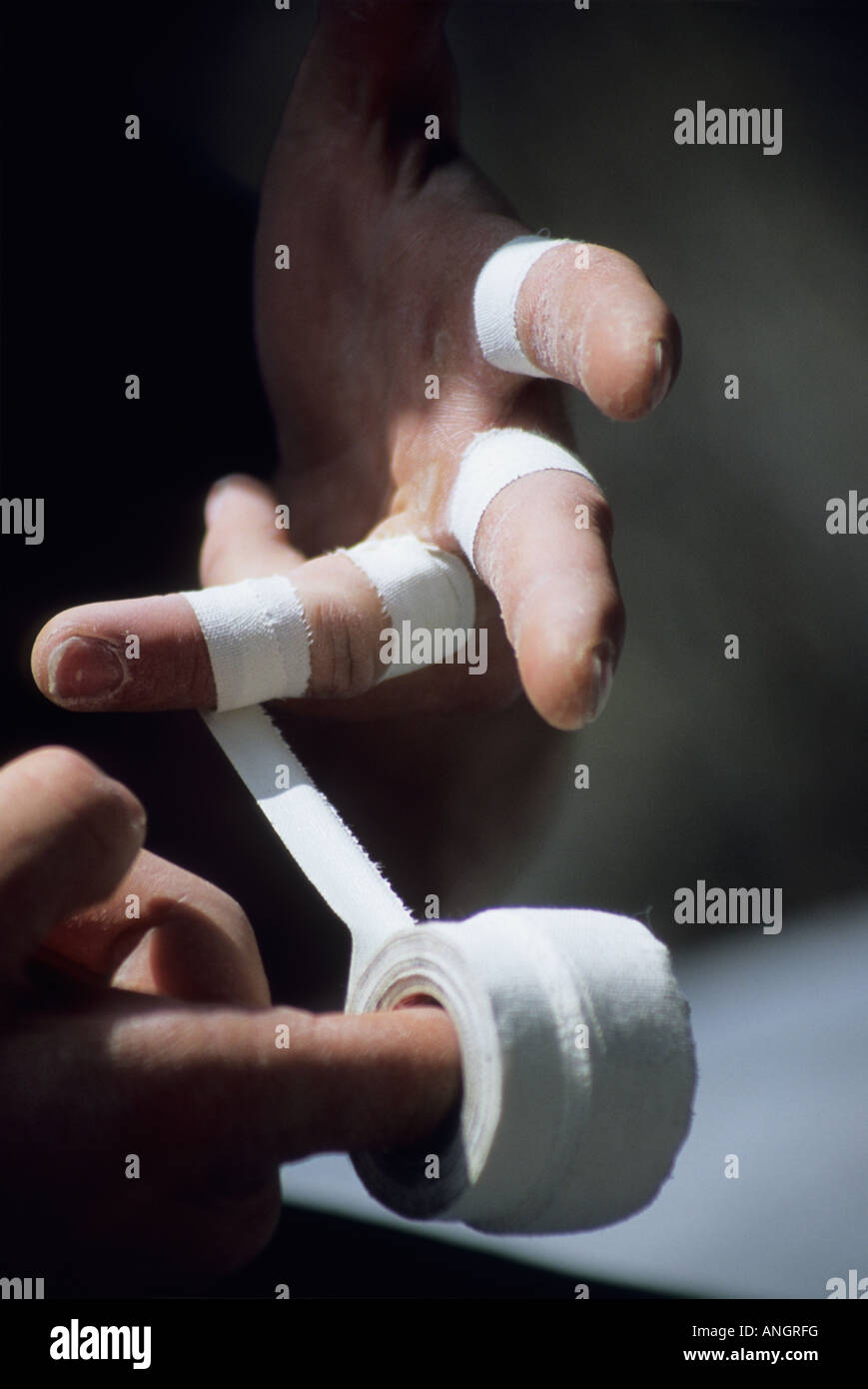 A climber taping his hands for the cracks that will greet him on