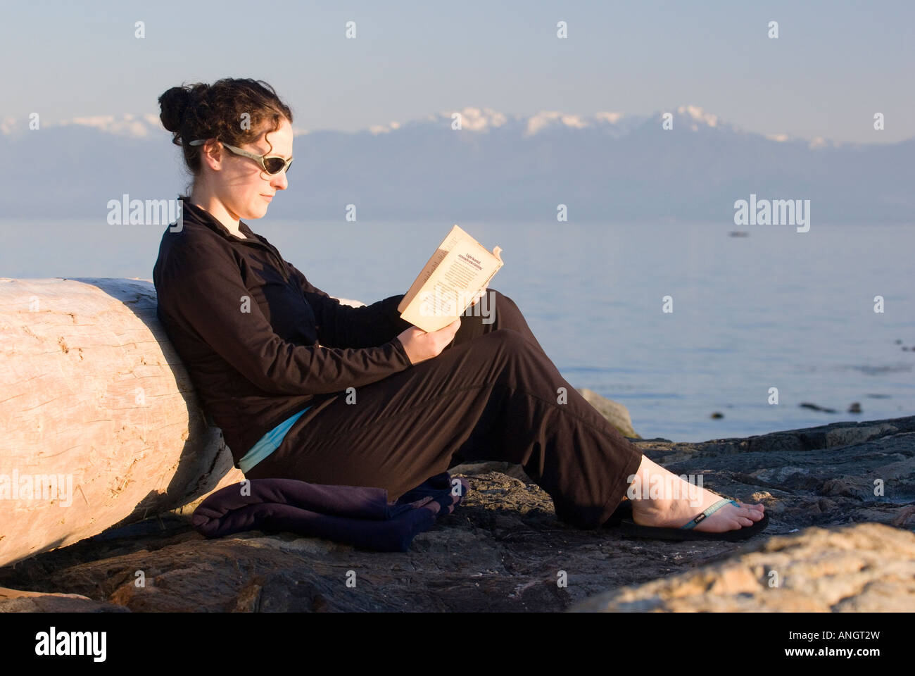 A woman reading a book on the beach near Victoria, Vancovuer Island, British Columbia, Canada. Stock Photo