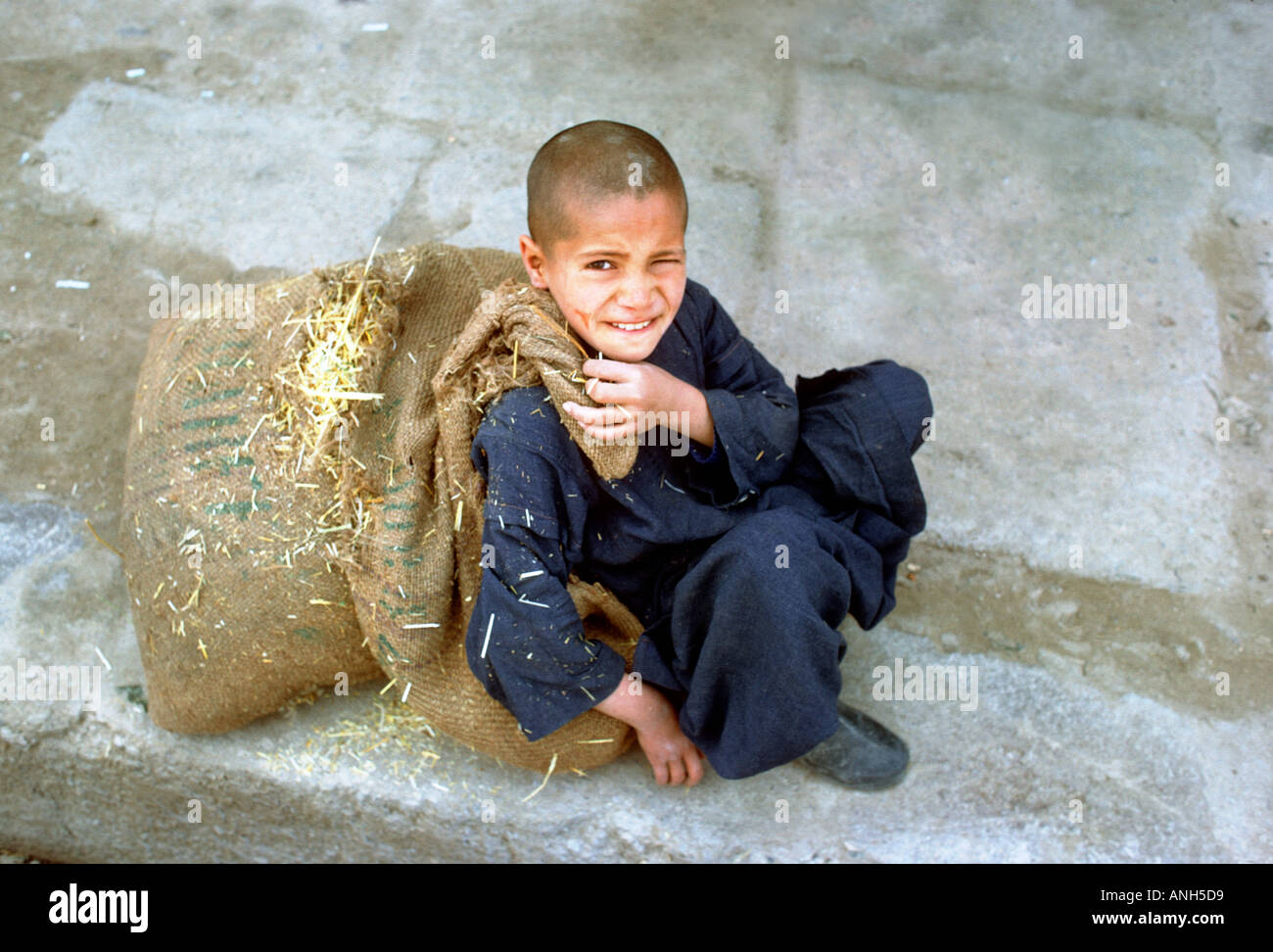 Afghanistan Afganistan Afghan Afghani boy resting with heavy sack Stock Photo