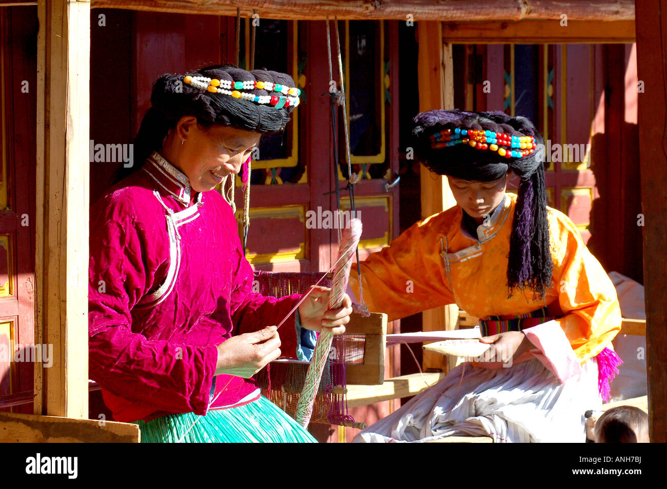Yunnan  Mosu minority tow sister  at home To work at a loom. Stock Photo