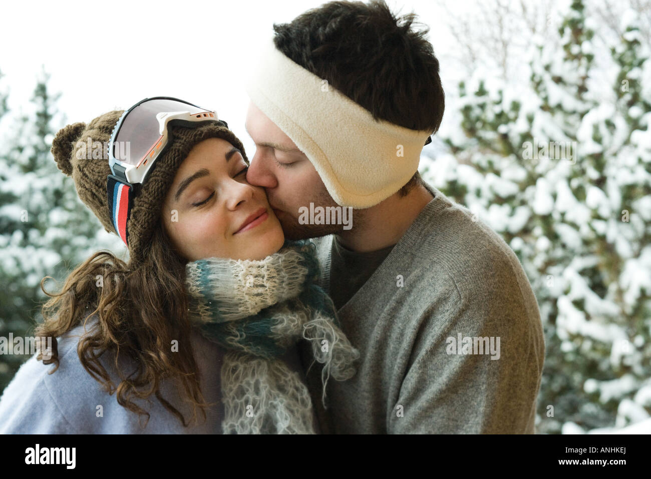 Young couple in winter clothing, man kissing woman on cheek Stock Photo