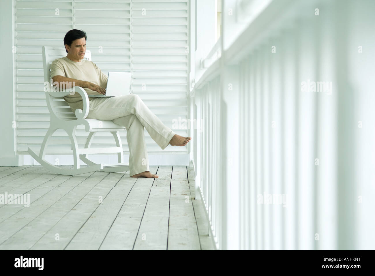 Man using laptop computer on porch Stock Photo - Alamy