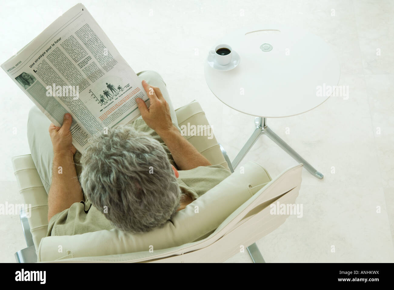 Man sitting, reading newspaper, high angle view Stock Photo