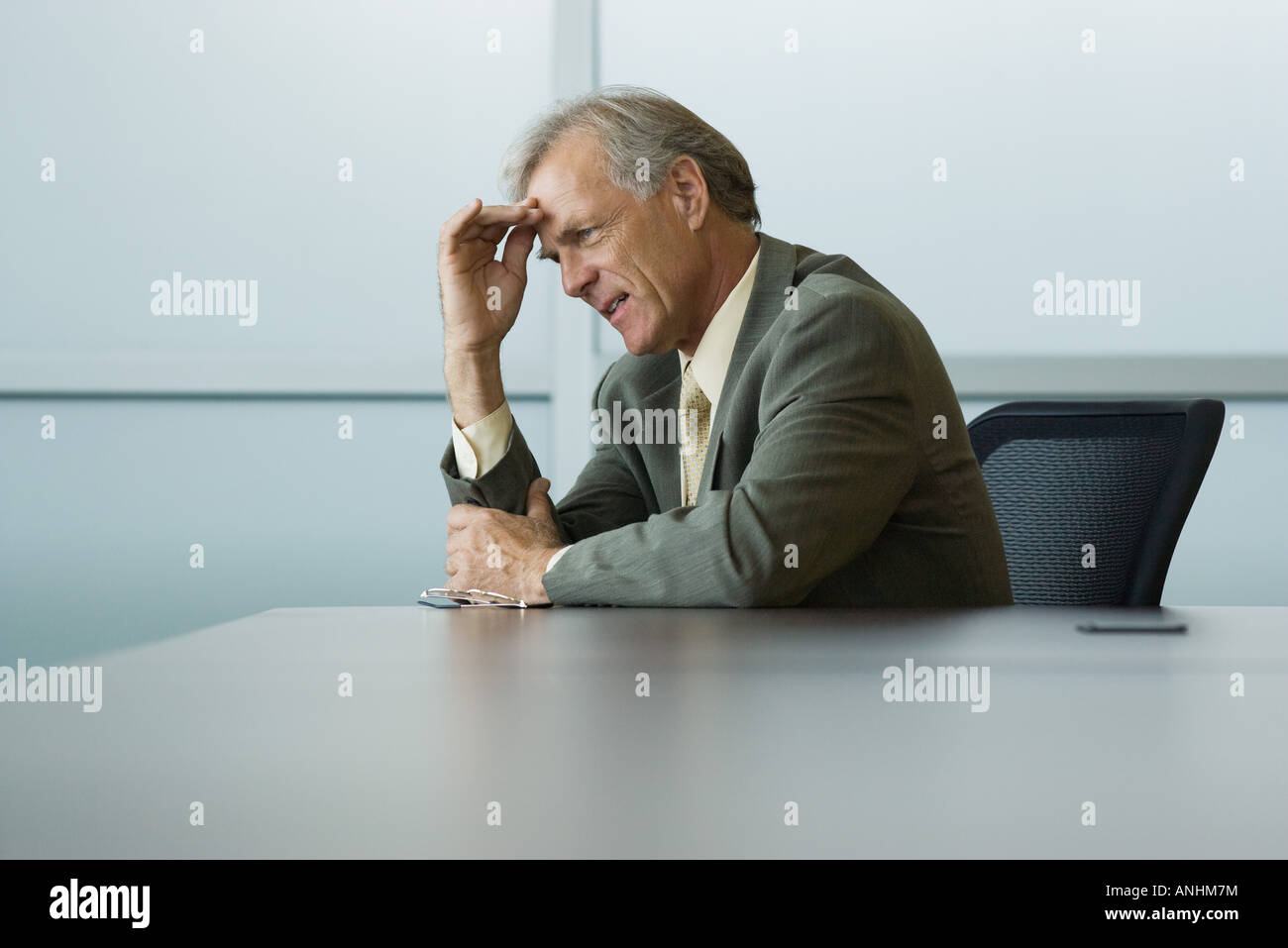 Businessman sitting, holding head, looking away Stock Photo
