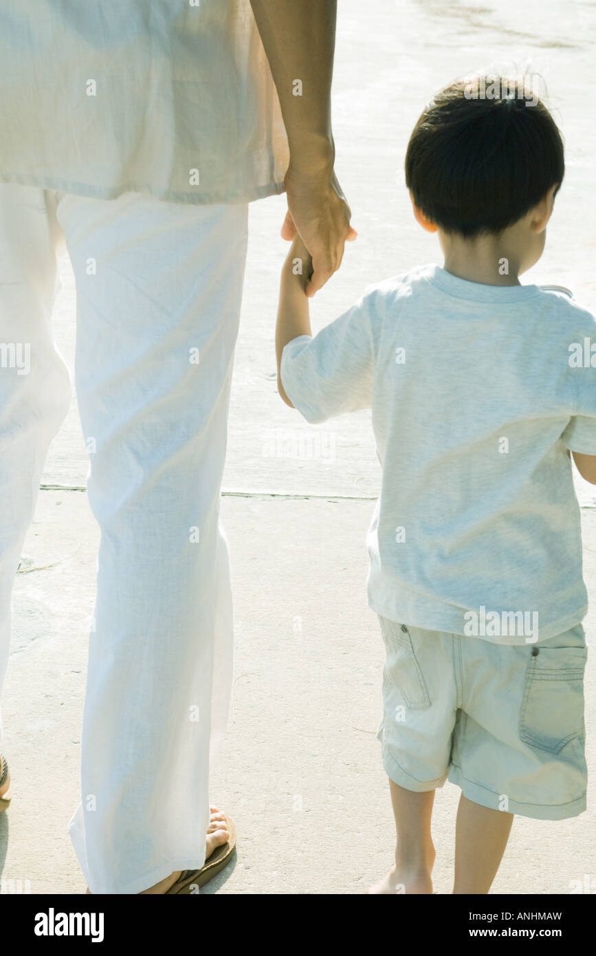 Father and son walking and holding hands, cropped rear view Stock Photo ...