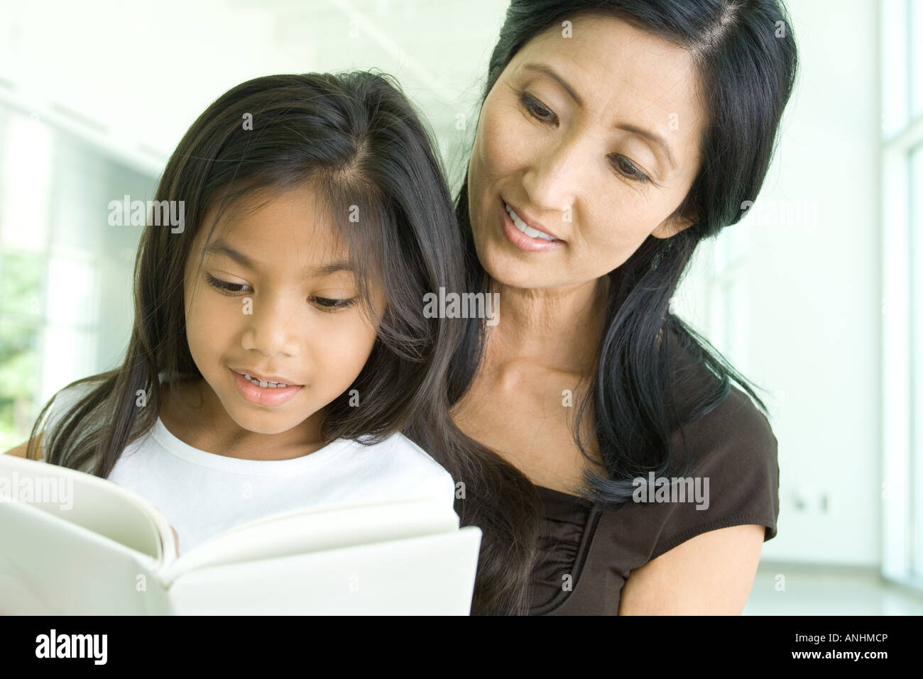 Mother and daughter reading book together, close-up Stock Photo