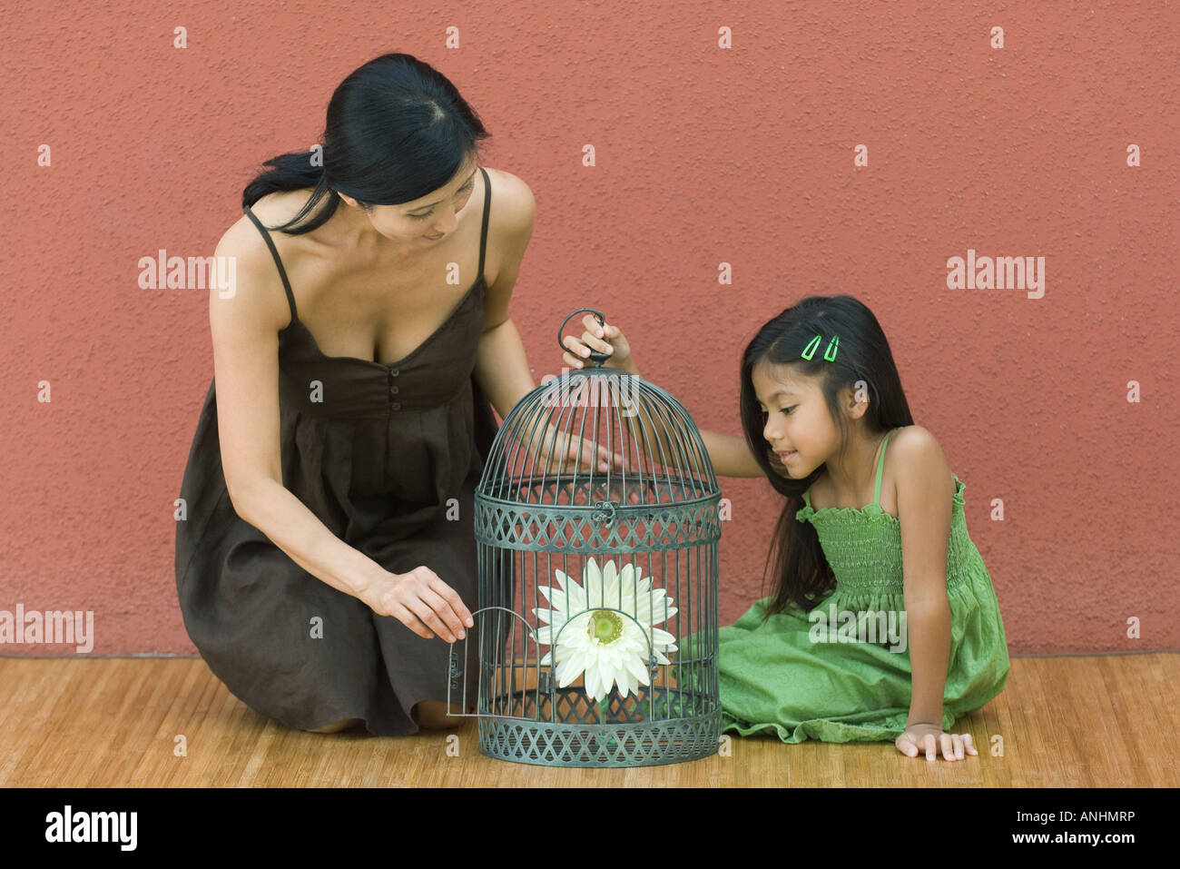 Woman and girl with birdcage containing flower, woman opening door Stock Photo