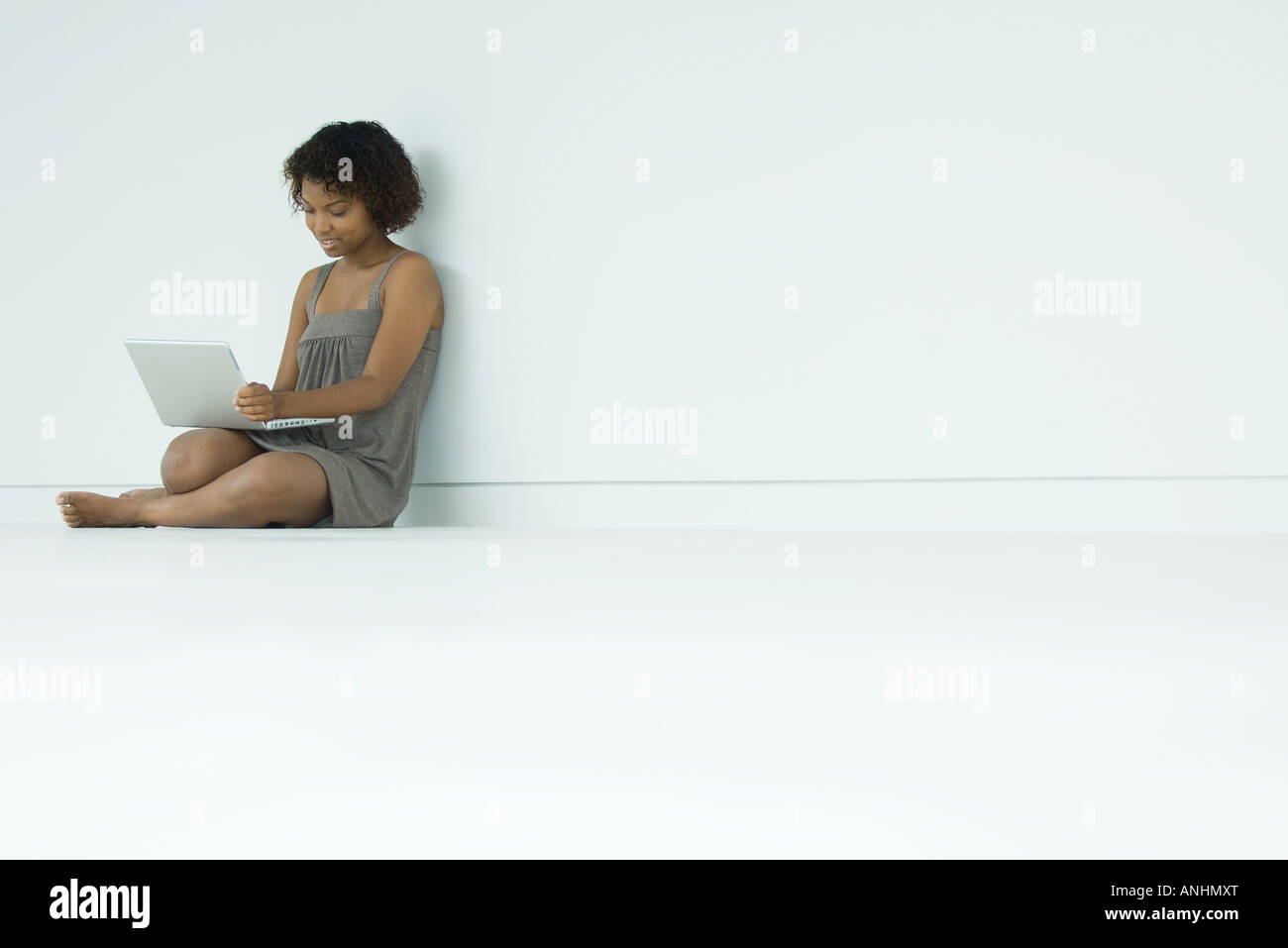 Young woman sitting on floor, using laptop Stock Photo