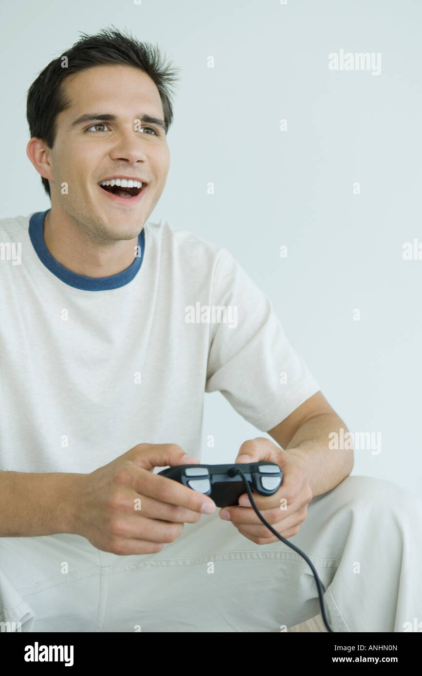 Young man playing video game, looking out of frame, smiling Stock Photo