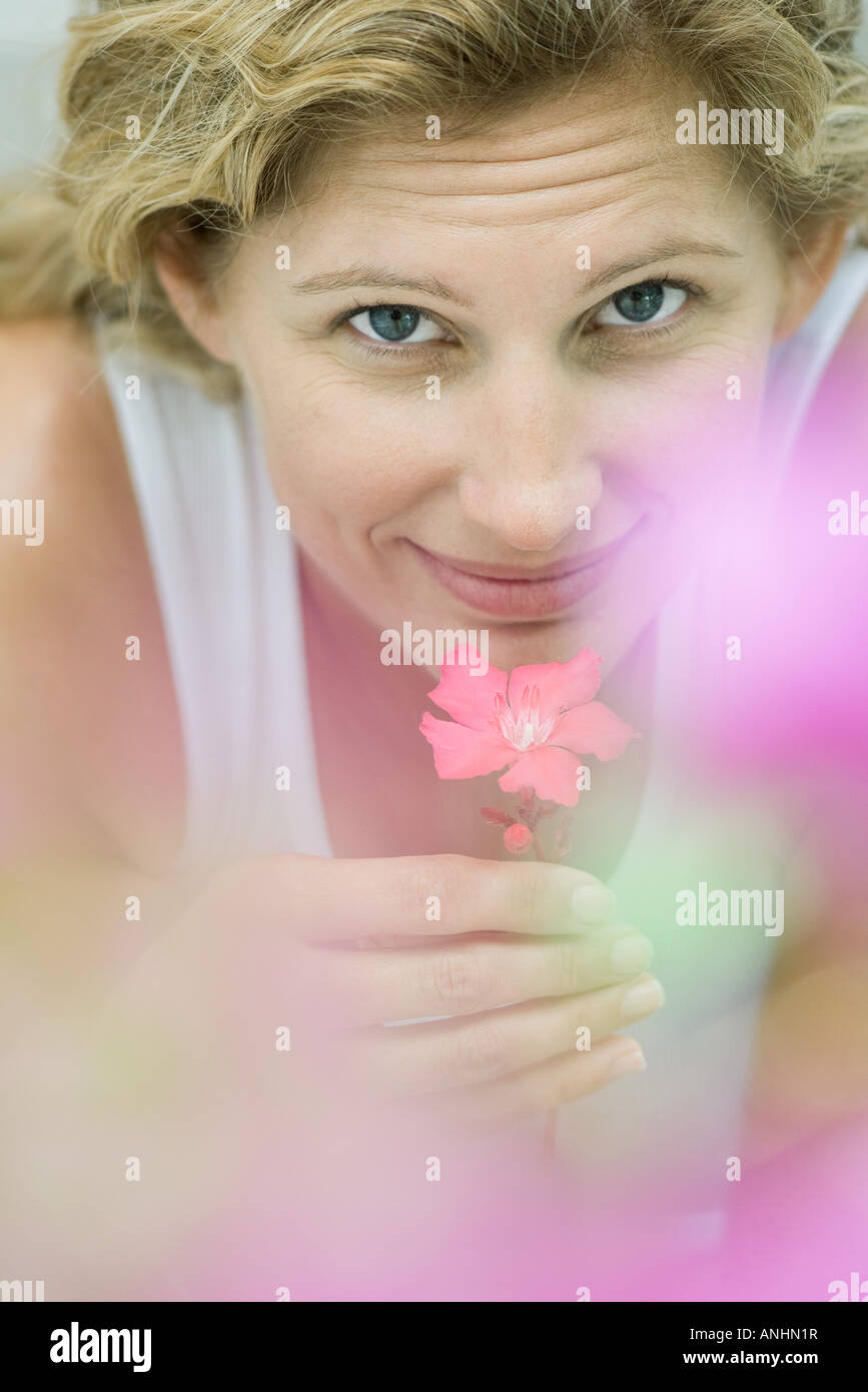 Woman smelling flower, looking at camera Stock Photo