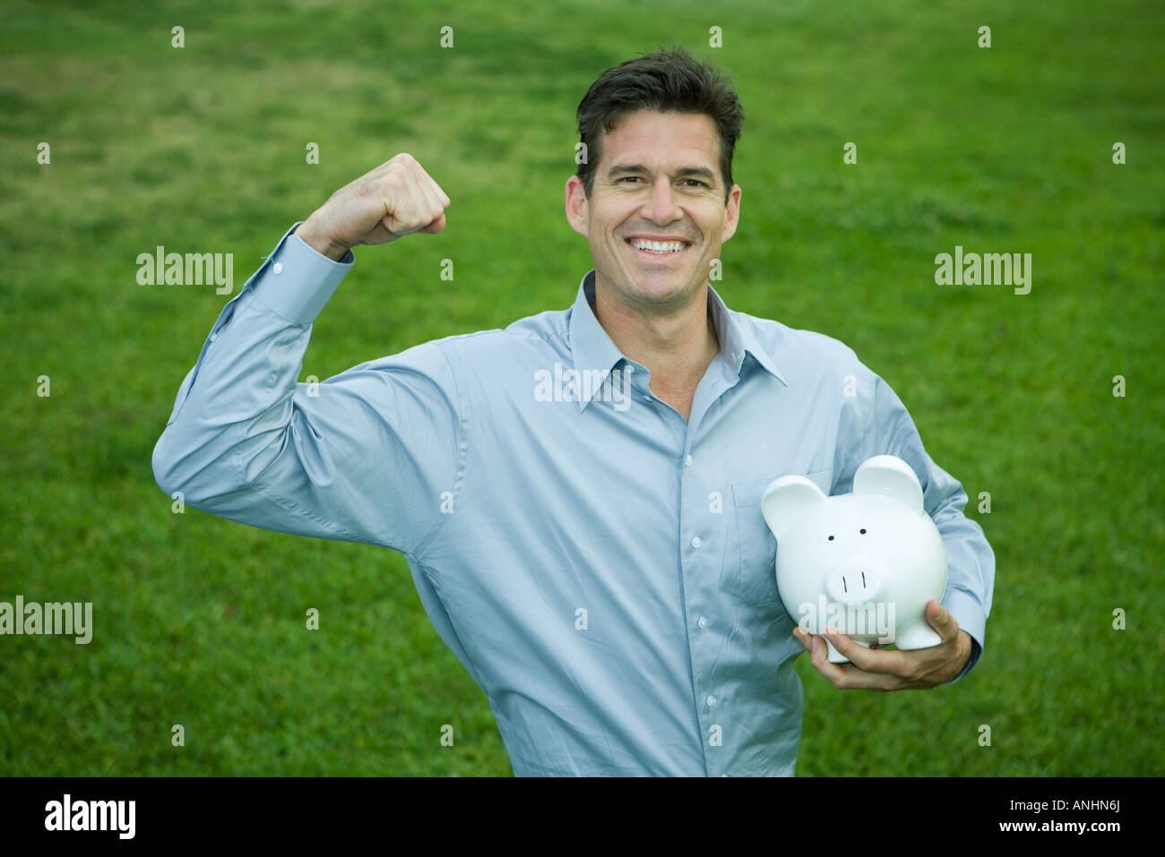 Man holding piggy bank, raising fist and smiling at camera Stock Photo ...